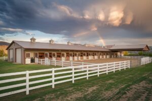 Selling Your Horse or Ranch Property in Oregon and Idaho: A Seller's Guide Professional real estate photo of a horse barn with covered arena and white four-board fencing